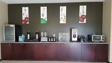 A kitchenette with a refrigerator, coffee maker, toaster, and microwave.
