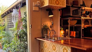 A kitchen with patterned cabinets, a sink, a stove, and a microwave. - Retro bungalow in organic garden oasis (Caulfield North)