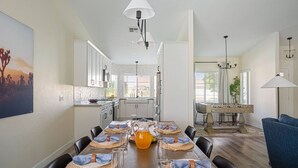 A dining area with a long table set for six, a coffee table with a pitcher, and a chandelier. - Swim-In Theater Oasis w/ Gated Pool Sleeps 12 (Indio)