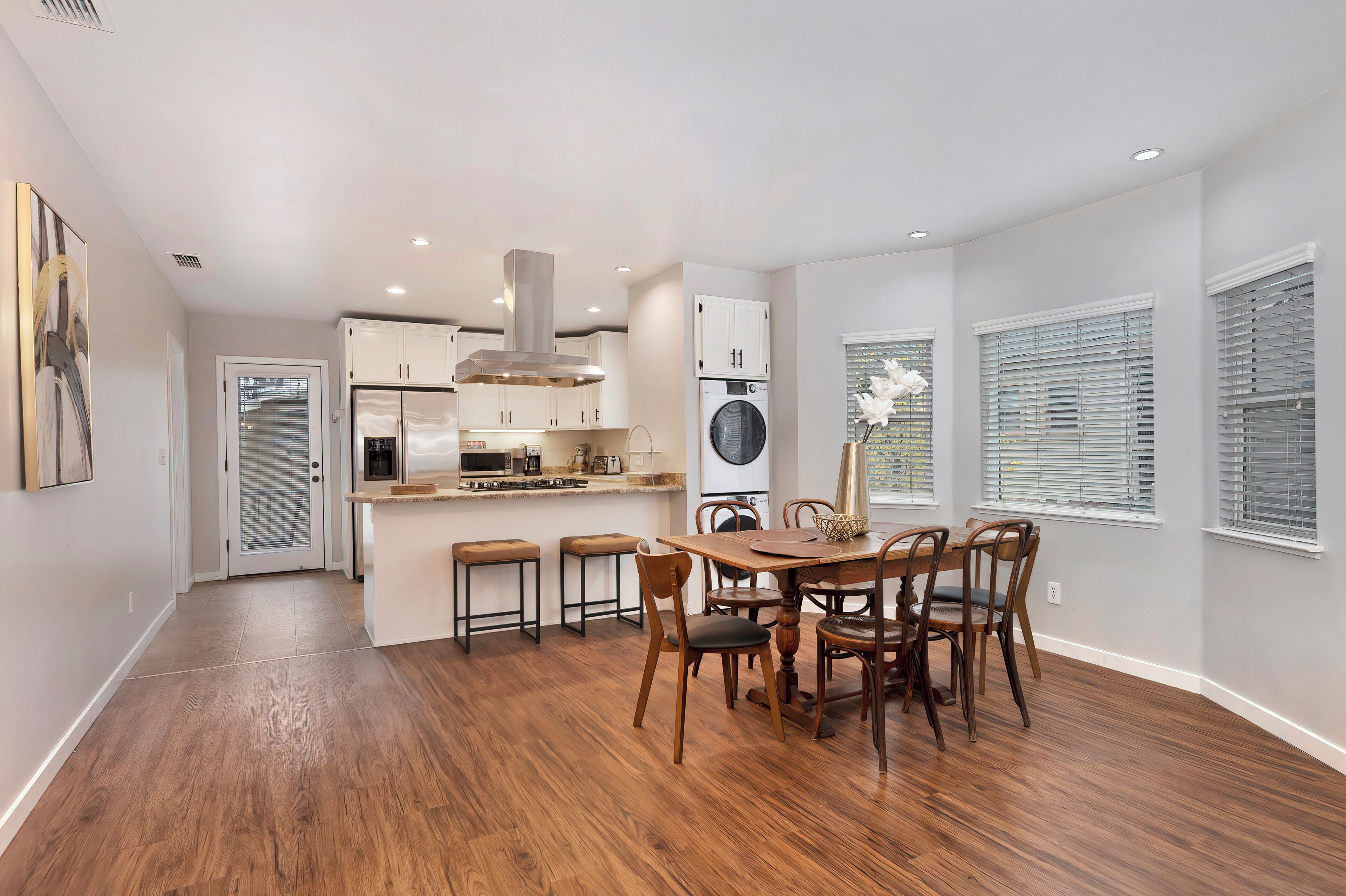 A modern kitchen with a central island, built-in appliances, and a dining area with a wooden table and chairs.