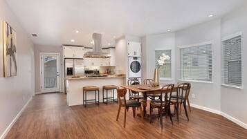 A modern kitchen with a central island, built-in appliances, and a dining area with a wooden table and chairs.