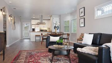A modern living room with a dark leather sofa, a round coffee table, and a red patterned rug.