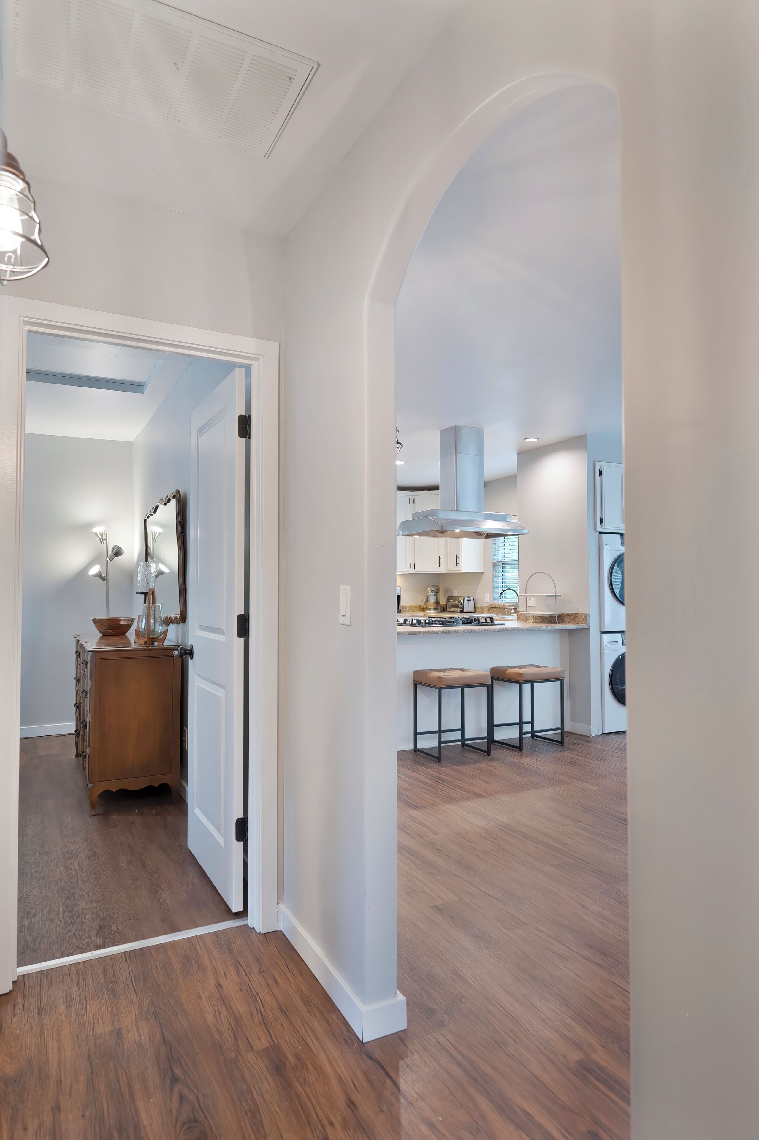 A modern kitchen with white cabinets, a stainless steel range hood, and a built-in oven.