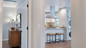 Une cuisine moderne avec des armoires blanches, une hotte de cuisinière en acier inoxydable et un four encastré.