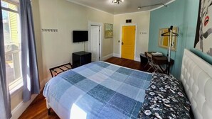 Una camera da letto con un letto, una scrivania, una sedia, un televisore e una porta.