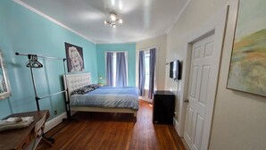 Una camera da letto con un letto, una scrivania, un armadio, una TV e una finestra con tende.