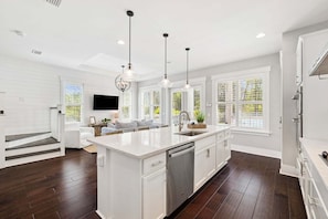 A modern kitchen with a central island, white cabinetry, and pendant lighting.