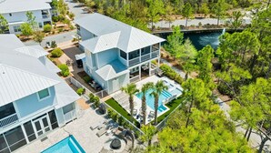 Un resort de varios pisos con piscina, rodeado de un bosque frondoso.