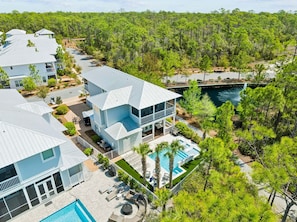 A multi-story resort with a pool, surrounded by dense forest.