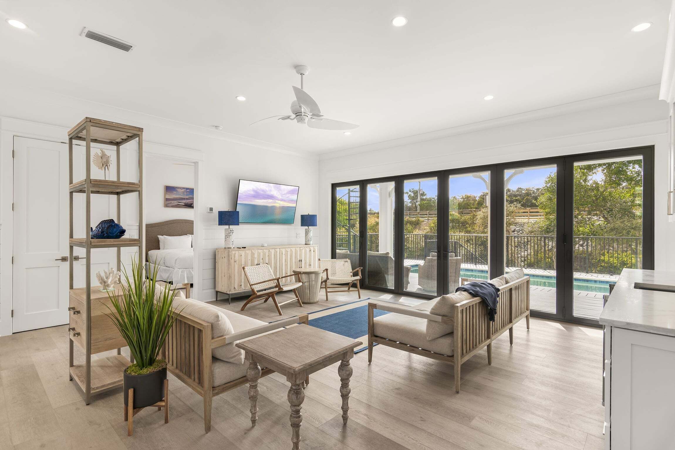 A spacious living area with a sofa, coffee table, and a TV. There is a balcony with a view of the outdoors.