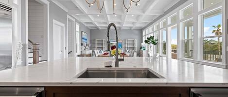 Cozinha moderna com ilha central, eletrodomésticos de aço inoxidável e lustre.