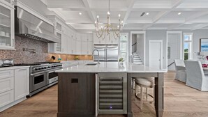 Una cocina moderna con una isla grande, electrodomésticos de acero inoxidable y una lámpara de araña.