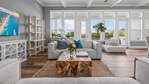 Un salón espacioso con un ventanal grande, una mesa de centro de madera y un sofá gris.