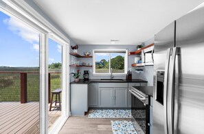 Cozinha moderna com uma janela grande, eletrodomésticos de aço inoxidável e vista para o exterior.