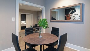 A dining area with a round table, chairs, a vase with a plant, and a framed abstract artwork on the wall. - 2BR Lower Westheimer Dream 01! Walkable to Montrose! (Houston)
