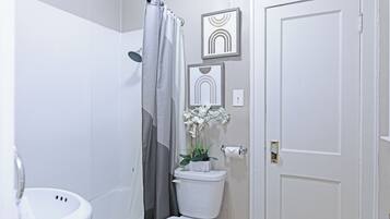 A bathroom with a toilet, shower curtain, and framed artwork on the wall.