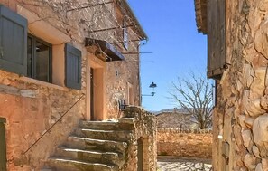 Un edificio de piedra con una puerta de madera y una escalera que sube a un muro de piedra.