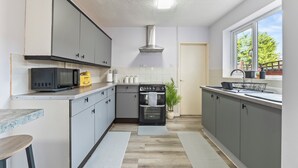 Una cucina moderna con mobili grigi, un forno a microonde, un forno e una finestra vista alberi.