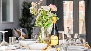 Un tavolo imbandito con piatti, bicchieri, una bottiglia di Campo Viejo Rioja e un vaso con fiori.