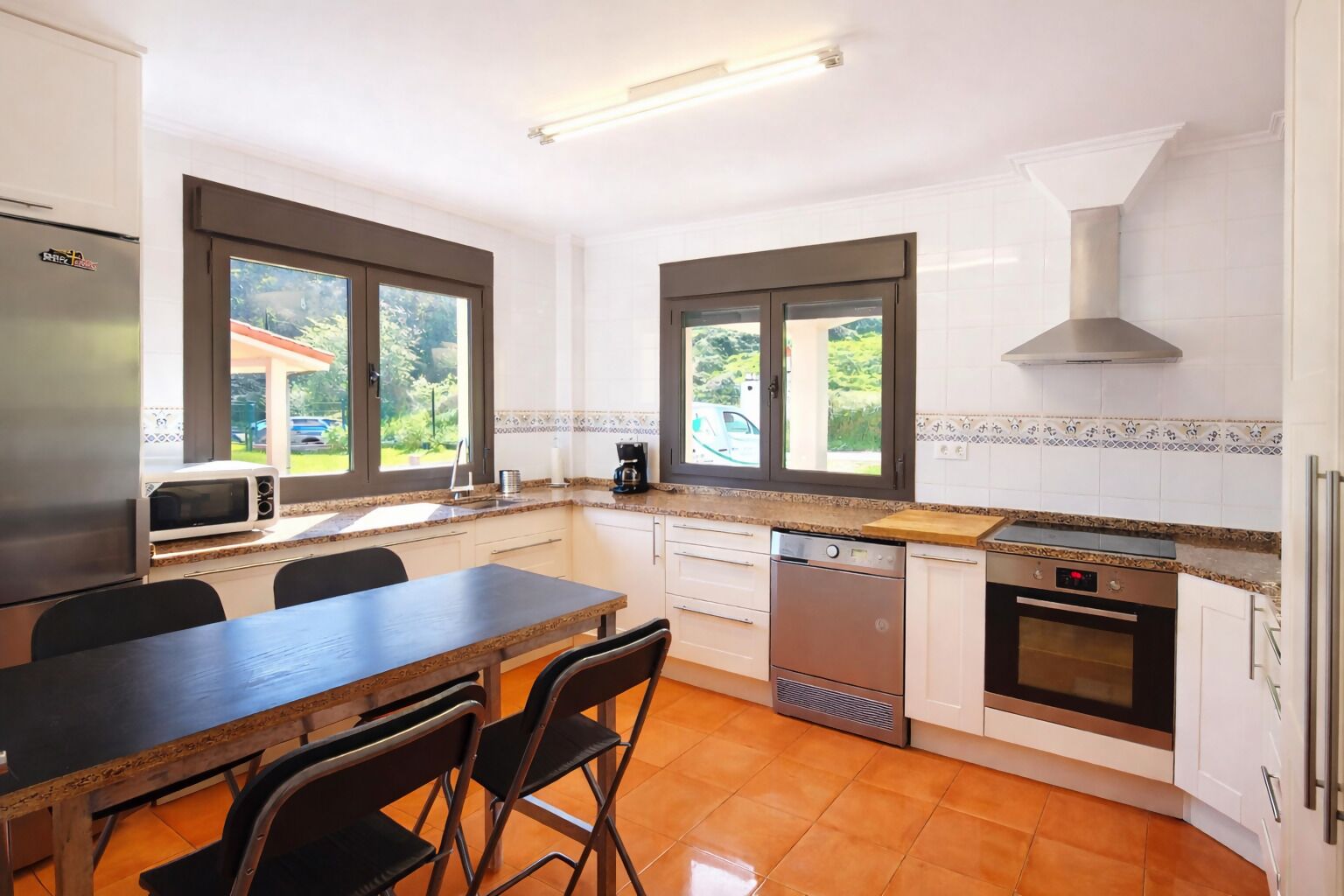 A modern kitchen with a dining area, large windows, and a built-in oven.