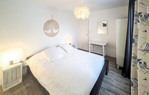 Ein ordentlich eingerichtetes Schlafzimmer mit einem Bett, Nachttischen, einem Kleiderschrank und einer Wanddekoration.