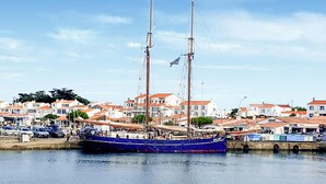 En hamn med en blå segelbåt förtöjd, omgiven av byggnader med röda tak.