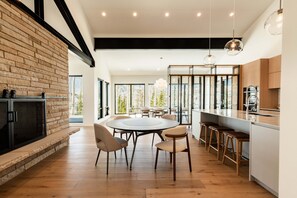 A modern kitchen with a brick wall, a round dining table, and bar stools. - Top of Deer Valley Flagstaff Mountain, walk to ski + hot tub (Park City)