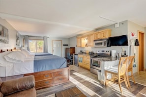 Une chambre avec un lit, un bureau et un coin cuisine.