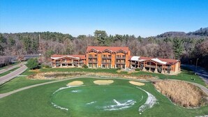 A lodge with a large, well-maintained golf course and a multi-story building with balconies. - Adventure Trails - Golf View + Hot tub | Waterpark (Wisconsin Dells)