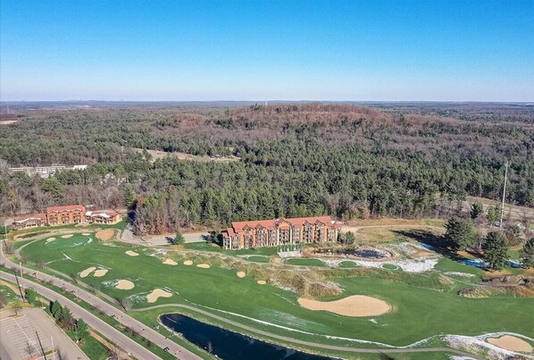 Een golfbaan met een clubhuis, omgeven door beboste gebieden.