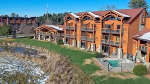 A multi-story lodge with balconies, a swimming pool, and a pond. - Adventure Trails - Golf View + Hot tub | Waterpark (Wisconsin Dells)