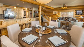 A wooden interior with a dining table set for four, a kitchen area, and a staircase. - Lake house 16 minutes from Yellowstone (West Yellowstone)