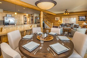 Un interior de madera con una mesa de comedor para cuatro, una zona de cocina y una escalera.
