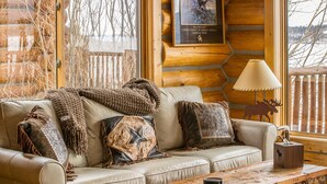 A cozy log cabin interior with a leather sofa, decorative pillows, a wooden coffee table, and a framed picture on the wall. - Lake house 16 minutes from Yellowstone (West Yellowstone)