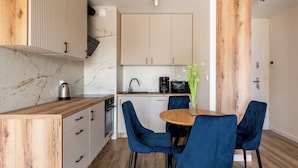 Une cuisine moderne dotée d’un plan de travail en bois, de placards intégrés et d’un coin repas avec des chaises bleues et une table ronde.