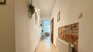 A hallway with a radiator, a brick wall, and a door leading to a dining area. - Daszyńskiego Spacious Apartment (Wrocław)
