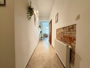 Ein Flur mit Heizkörper, Backsteinwand und einer Tür zum Essbereich.