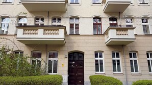 A multi-story building with a symmetrical facade, multiple windows, and a central entrance with a dark-colored door. - Daszyńskiego Spacious Apartment (Wrocław)