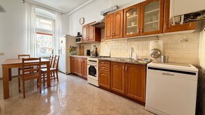 A kitchen with wooden cabinets, a white refrigerator, a stove, and a dishwasher. - Daszyńskiego Spacious Apartment (Wrocław)