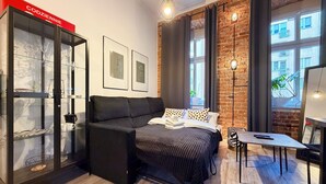 Ein modernes Zimmer mit Bett, einer Couch, einem Schreibtisch und einer Glastruhe.