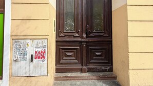 Eine braune Holztür mit kleinem Fenster, ein Schild darüber und ein Poster an der Wand darunter.
