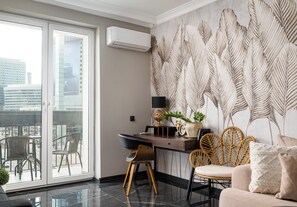 Ein modernes Zimmer mit Schreibtisch, Stühlen, einer Couch, einem großen Fenster und einer Wand mit dekorativem Blattmuster.