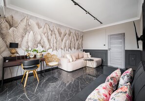 Ein modernes Wohnzimmer mit einer Couch, einem Schreibtisch, einem Sessel, einer Wanddekoration und einer Tür.