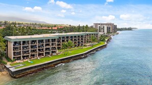 A hotel with multiple balconies, a pool area, and a view of the ocean. - SUMMER SALE! Remodeled Oceanfront 1BR Steps to Pool & Ocean - Kahana Reef 107 (Lahaina)