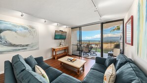 A modern living room with a sofa, coffee table, and artwork on the walls. - SUMMER SALE! Remodeled Oceanfront 1BR Steps to Pool & Ocean - Kahana Reef 107 (Lahaina)
