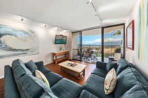 A modern living room with a sofa, coffee table, and artwork on the walls. - SUMMER SALE! Remodeled Oceanfront 1BR Steps to Pool & Ocean - Kahana Reef 107 (Lahaina)