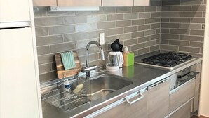 Una cocina moderna con un lavamanos de acero inoxidable, una estufa a gas y armarios de madera.