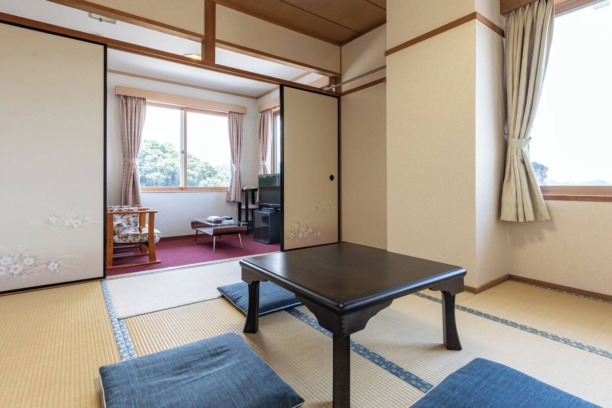 A traditional Japanese room with tatami flooring, a low table, and sliding doors.