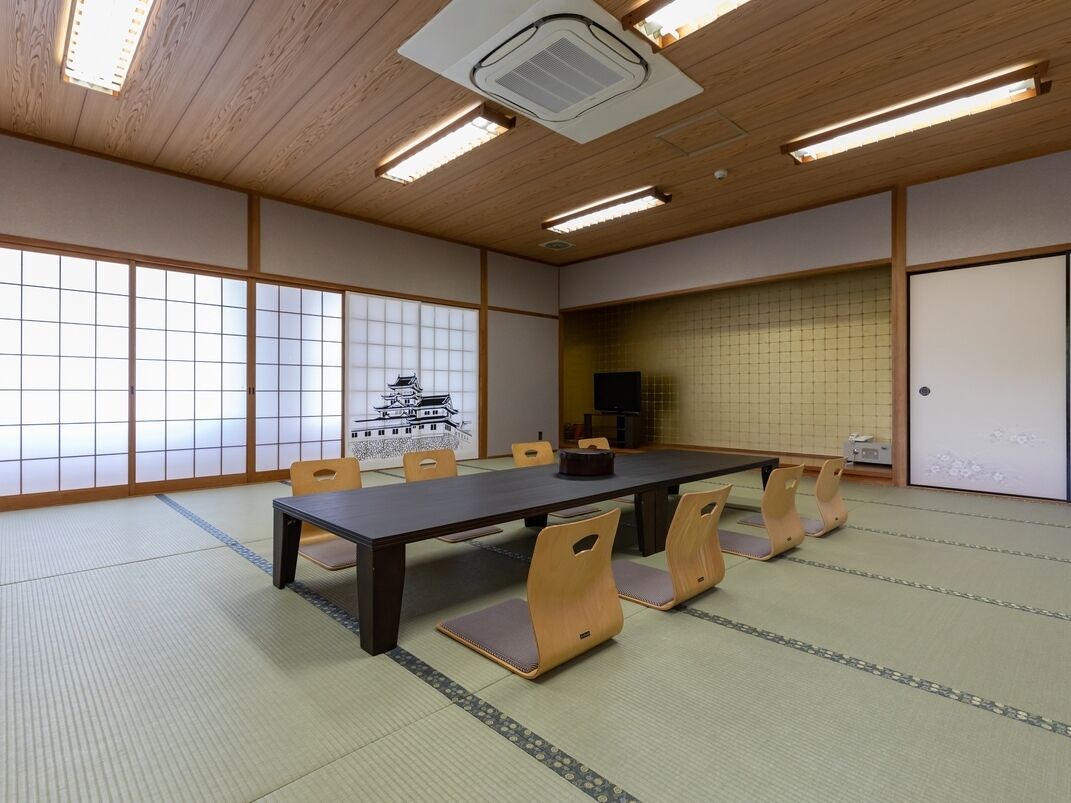 A traditional Japanese room with tatami flooring, a low table, and wooden chairs.