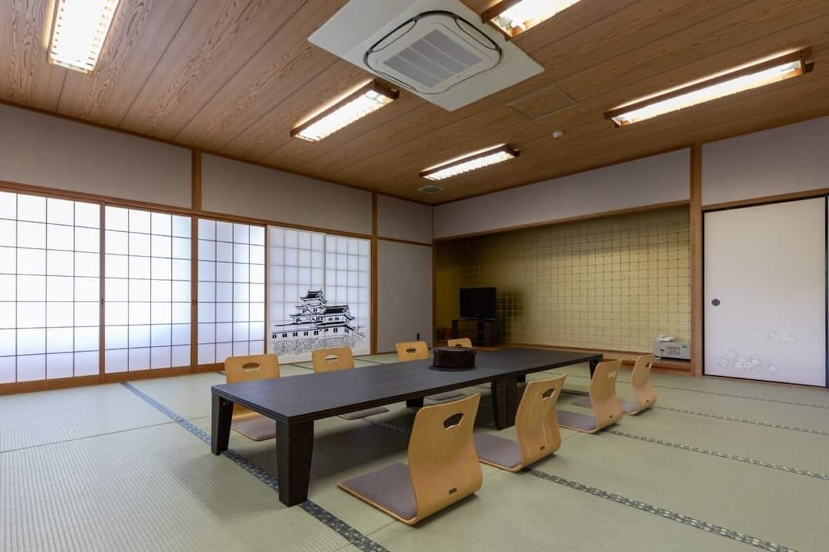 A traditional Japanese room with tatami flooring, a low table, and wooden chairs.